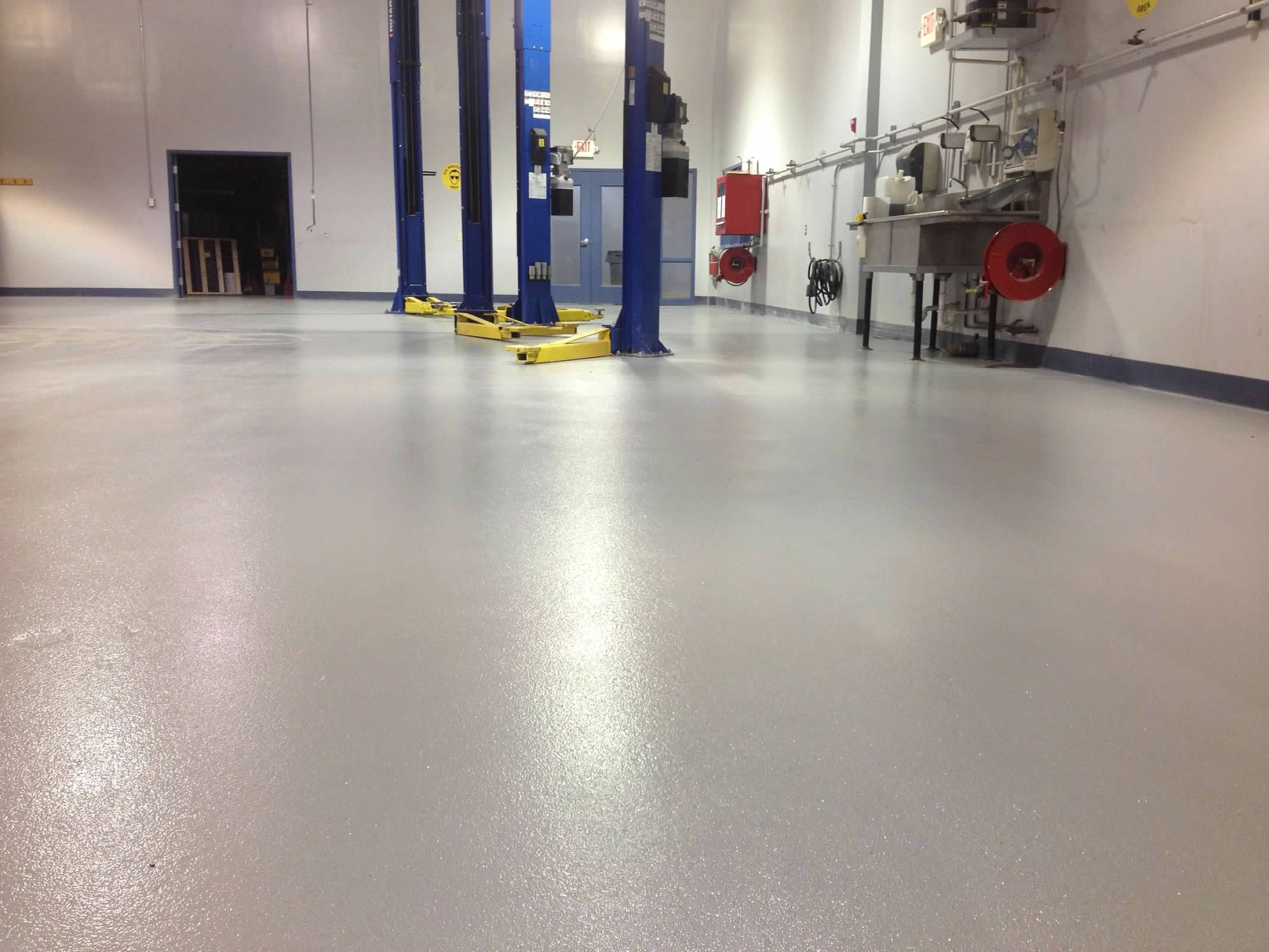 Coated floor with large car jacks and a sink in the background