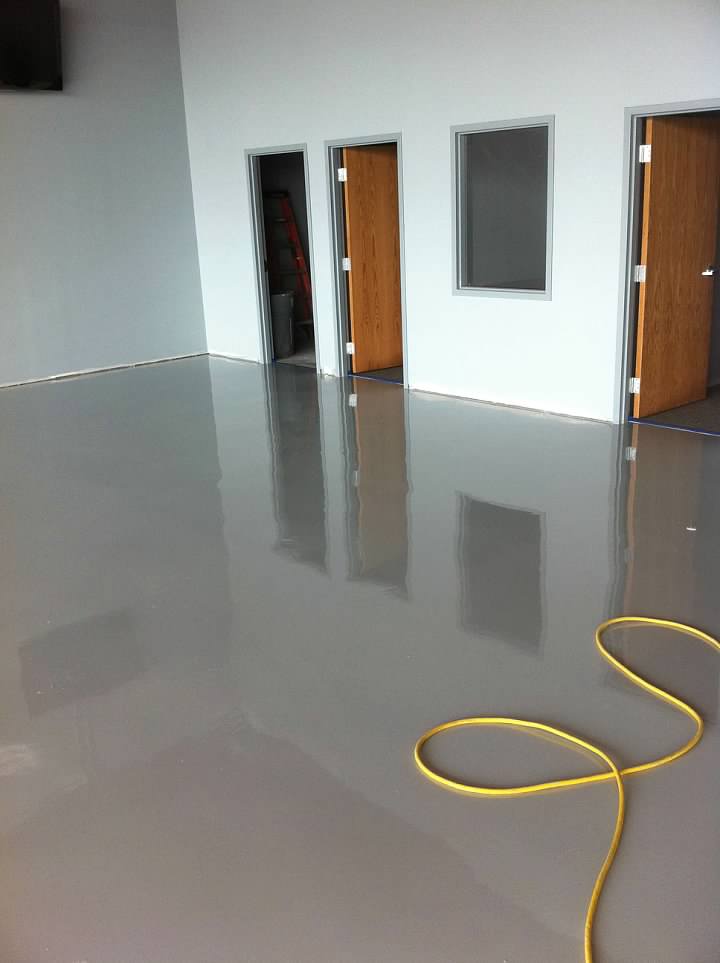 Coated floor in an empty room and a hose laying on the floor